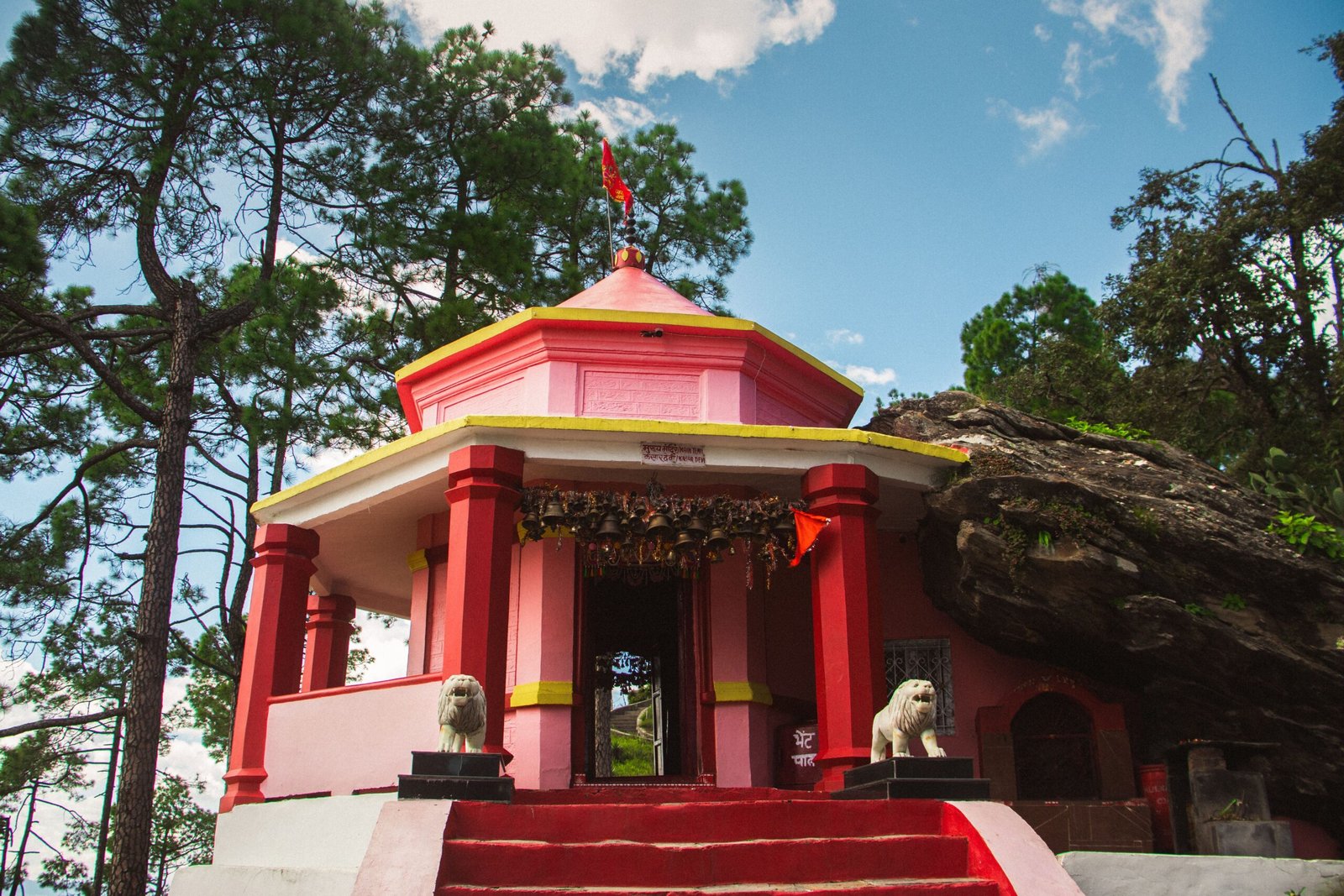 Beautiful Hindu temple amidst pine trees in Binsar, Uttarakhand under a clear sky.